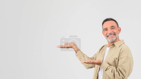 Vieil homme souriant présentant avec un geste de main ouverte, isolé sur un fond blanc, panorama avec espace de copie