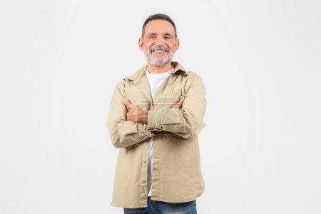 This image captures a senior man with a friendly expression and arms crossed, symbolizing confidence and experience, isolated on a white backdrop