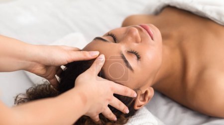 Téléchargez les photos : Moment intime d'une dame recevant un massage délicat du visage, soulignant la beauté afro-américaine - en image libre de droit