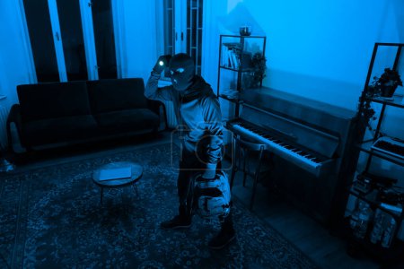 A thief in a mask with a flashlight is captured while rummaging through an apartment at night, depicting a scene of crime and burglary