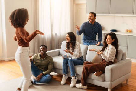 Foto de Una cautivadora escena de jóvenes amigos multirraciales disfrutando de una animada conversación y riéndose juntos en casa - Imagen libre de derechos
