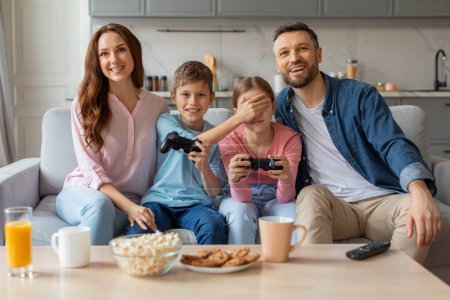 Téléchargez les photos : Cette famille européenne respire l'amour et le contentement alors qu'ils posent chaleureusement lors d'une séance de jeu vidéo confortable à la maison, nourrissant des relations affectueuses - en image libre de droit