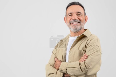 A happy elderly man stands with folded arms and a beaming smile, representing contentment and joy in retired life, isolated on white, copy space