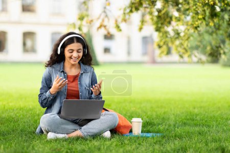 Téléchargez les photos : Étudiante hindoue s'engageant dans un appel vidéo sur son ordinateur portable dans un parc, représentant la technologie dans l'éducation - en image libre de droit