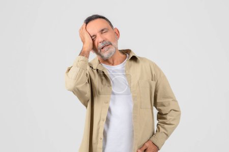 Un homme âgé tient sa tête, dépeignant un moment stressant ou douloureux, isolé sur blanc, ont la migraine