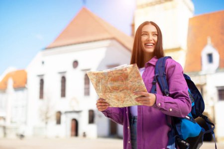In einer europäischen Umgebung erkundet eine Millennials-Dame ihre Umgebung mit einer Landkarte und verkörpert den neugierigen Geist eines Studenten im Freien
