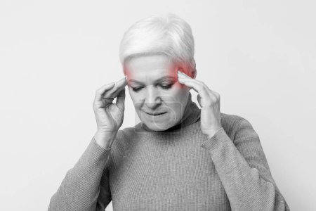 Téléchargez les photos : Femme âgée âgée européenne montrant les effets d'une migraine avec une aura rouge éditée autour de la tête, représentant les problèmes de santé dans s3niorlife - en image libre de droit