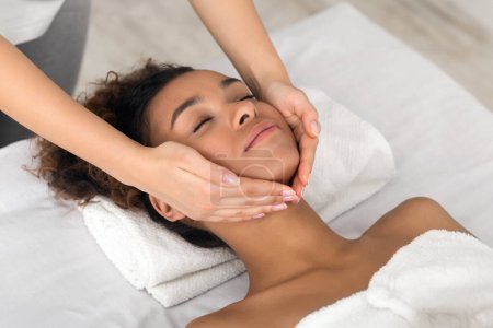 Téléchargez les photos : Une femme afro-américaine bénéficie d'un massage spa apaisant axé sur son cou et ses épaules, incarnant la relaxation et le bien-être en tant que peuple noir embrasser les routines d'autosoin - en image libre de droit
