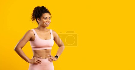 Foto de Una radiante dama afroamericana con una sonrisa brillante posa con confianza en el atuendo de fitness sobre un fondo amarillo aislado - Imagen libre de derechos