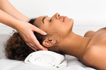 Foto de Terapeutas manos realizando un masaje de spa relajante en una cabeza de las mujeres afroamericanas en el salón de belleza - Imagen libre de derechos