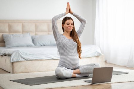 This pregnant european lady is following an online prenatal yoga class at home accentuating modern pregnancy practices