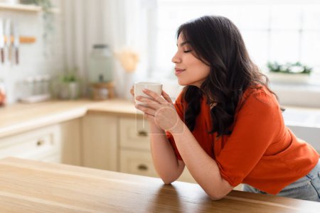 Photo for A serene moment captured as a middle eastern zoomer woman enjoys a coffee break, reflecting tranquility and comfort in her home - Royalty Free Image