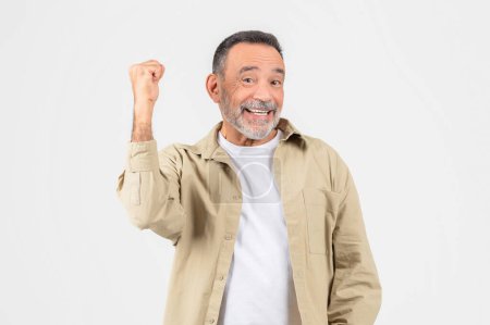 Photo for A joyful elderly man is isolated against a white backdrop, celebrating with a fist pump, embodying a positive, retired lifestyle - Royalty Free Image