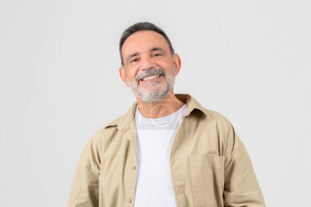 A cheerful senior man with hands in his jacket pockets gives off a relaxed and casual vibe, isolated on a white background conveying approachability
