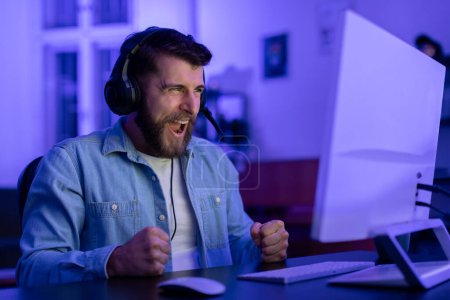 Photo for A millennial guys intense reaction exemplifies the emotional highs and lows of gaming at home, showcasing the potential for addiction within the gamer culture - Royalty Free Image