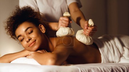 Photo for Thai herb compress massage. Woman relaxing in beauty spa, lying with closed eyes - Royalty Free Image