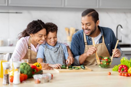 Foto de Una familia afroamericana feliz trabaja junta cortando verduras en la cocina, demostrando la cooperación familiar y una vida saludable - Imagen libre de derechos