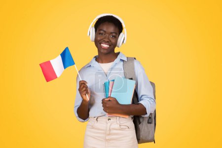 Foto de El joven estudiante negro sosteniendo orgullosamente una bandera francesa simboliza la conciencia internacional entre los zoómeros Fondo amarillo aislado y vibrante - Imagen libre de derechos