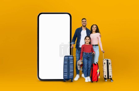 Famille moyen-orientale avec sacs de voyage sur fond jaune, prêts à présenter des applications numériques et des offres en ligne pour les voyages en famille