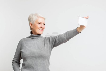 Eine fröhliche ältere Frau aus Europa macht ein Selfie und fängt die Essenz eines modernen s3niorlife mit Technologie ein