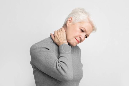 Femme âgée européenne éprouvant des douleurs au cou, transmettant les luttes et les aspects sanitaires du vieillissement et de la s3niorlife
