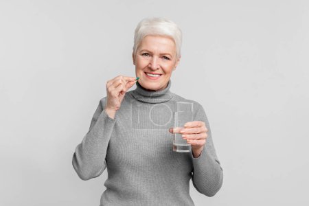 This image captures an elderly woman preparing to take medication, showing a common aspect of s3niorlife for a european senior woman