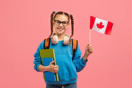 Ein aufgewecktes Teenie-Mädchen hält die kanadische Flagge in der Hand, die eine Verbindung zur kanadischen Kultur oder zum Studium in einem isolierten rosa Rahmen darstellt.