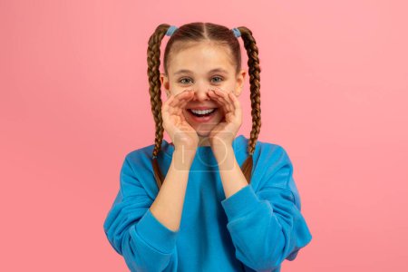 Foto de Una linda adolescente con trenzas haciendo anuncio, aislada en rosa, representa la alegría y espontaneidad de un joven caucásico - Imagen libre de derechos