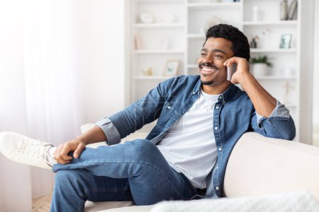 Téléchargez les photos : Un homme afro-américain profite d'un moment paisible dans sa maison sereine, incarnant un sentiment de calme et de satisfaction dans un environnement familier - en image libre de droit