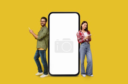 Un hombre y una mujer pareja Multiracial con una gran pantalla de teléfono inteligente en blanco para los vendedores en el fondo colorido estudio