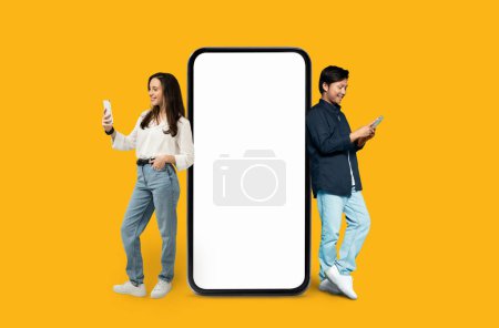 Two friends Multiracial man and woman interacting with a large smartphone with empty screen on an orange background