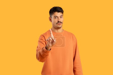 A man wearing an orange sweater is pointing at an unknown object or direction. He appears engaged and focused on the target, possibly indicating something of interest or importance.