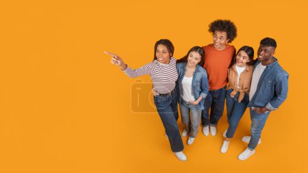 A forward-thinking group of friends look and point upward together, symbolizing goals and aspirations in a multiethnic context, isolated on a yellow background, copy space