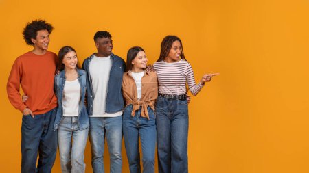 Téléchargez les photos : Cinq jeunes amis divers debout sur un fond orange, interagissant et regardant joyeux, espace de copie - en image libre de droit