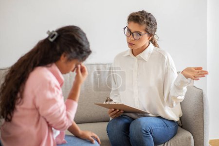 Un terapeuta compasivo está ofreciendo apoyo atento a una joven angustiada que parece ser emocional durante una sesión de asesoramiento