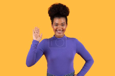 Une femme hispanique portant une chemise violette est vue gesticuler avec sa main. Son expression suggère qu'elle communique ou insiste sur un point