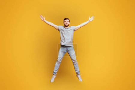 Téléchargez les photos : Un homme saute énergiquement dans les airs, les bras tendus comme pour atteindre le ciel dans un moment de mouvement intense et de liberté. - en image libre de droit