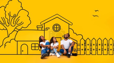 Glückliche schwarze Familie aus drei Familienvätern, Mutter und Tochter, die auf dem Fußboden sitzen und das illustrierte Haus ihrer Träume über gelbem Wandhintergrund betrachten