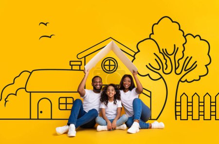 A cheerful African American family, is sitting closely together, smiling widely, and posing against a vibrant yellow backdrop with playful drawings of a house