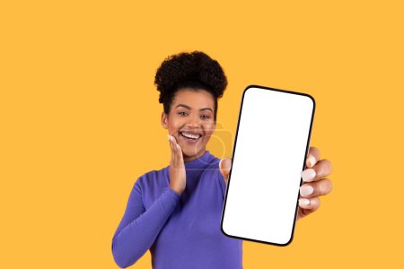 Die hispanische Frau hält sich ein Handy vor das Gesicht, den Blick auf den Bildschirm gerichtet. Sie scheint mit der Kommunikation oder dem Anzeigen von Inhalten auf dem Gerät beschäftigt zu sein.