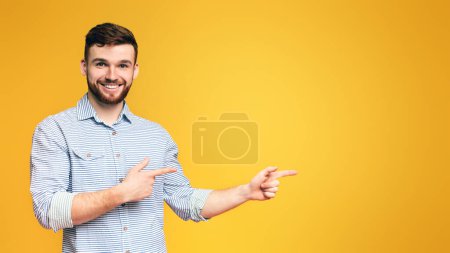 Stylischer rothaariger bärtiger Millennial-Mann zeigt auf leeren Raum und zeigt neues Angebot auf orangefarbenem Hintergrund