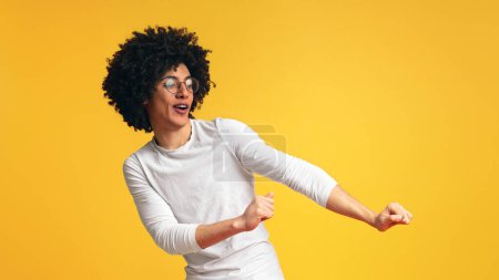 Téléchargez les photos : Joyeux buissonneux noir homme s'amuser, danser sur fond de studio orange - en image libre de droit