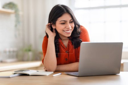 Eine fokussierte Frau aus dem Nahen Osten, die zu Hause am Laptop lernt oder arbeitet, verkörpert ein modernes Bildungsambiente