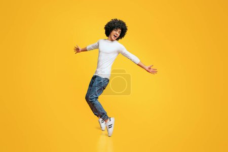 Téléchargez les photos : Jeune homme afro-américain drôle debout sur ses orteils sur fond orange - en image libre de droit