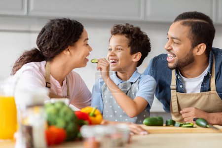 Foto de Una conmovedora instantánea de una familia afroamericana riendo y disfrutando de un aperitivo ligero juntos en la cocina, celebrando juntos - Imagen libre de derechos