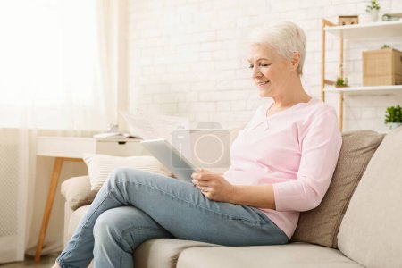 Foto de Ten algo de papeleo. Mujer mayor que trabaja con documentos y tabletas digitales en casa, espacio libre - Imagen libre de derechos