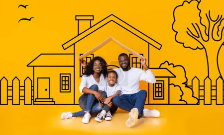 Happy African American family of three father mother and daughter sitting on floor over illustrated house of their dreams over yellow wall background, parents holding a roof