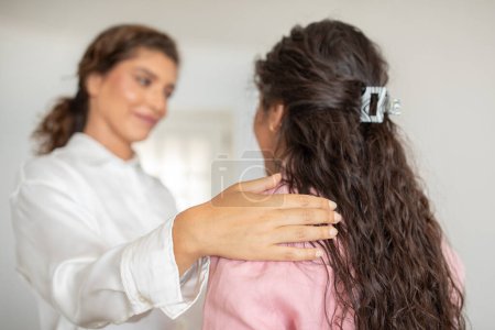 A woman in white offers comfort with a touch on anothers lady shoulder in a serene setting, therapy session, mental health concept