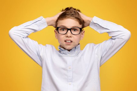 Photo for OMG Shocked teen boy in glasses touching his head in amazement, orange background - Royalty Free Image