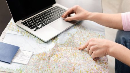 Eine nicht wiedererkennbare Frau sitzt an einem Tisch und benutzt einen Laptop, der eine Landkarte auf dem Bildschirm anzeigt. Die Dame tippt und interagiert mit der digitalen Landkarte.